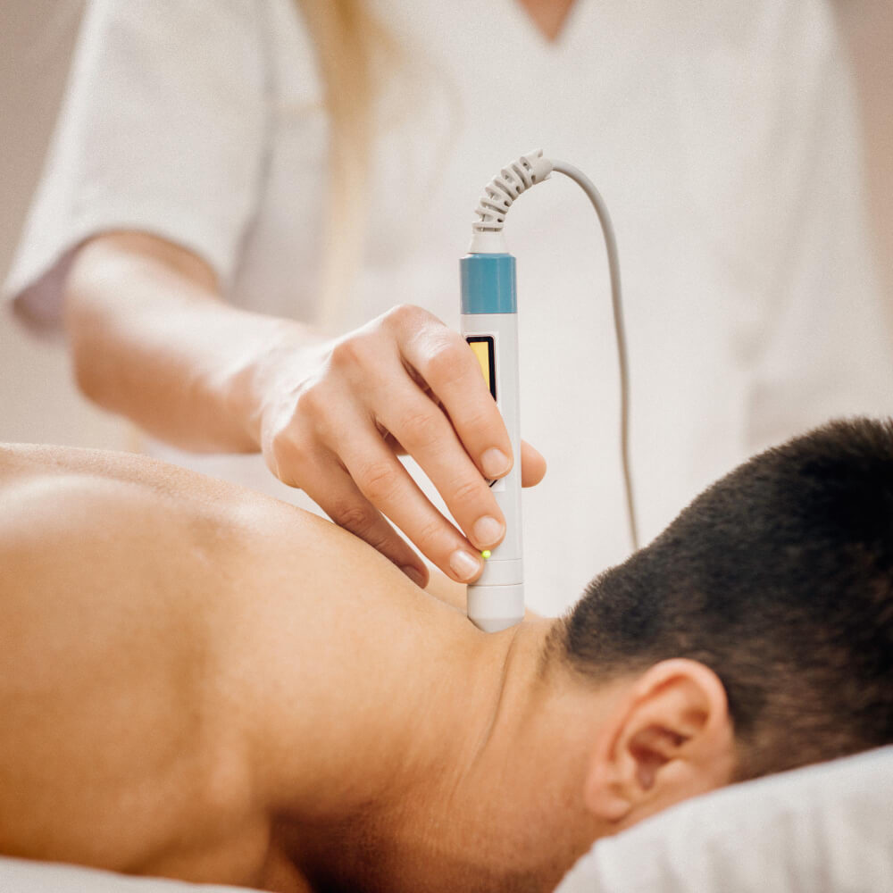 A therapist using a therapeutic device on a patient's neck during a massage session.